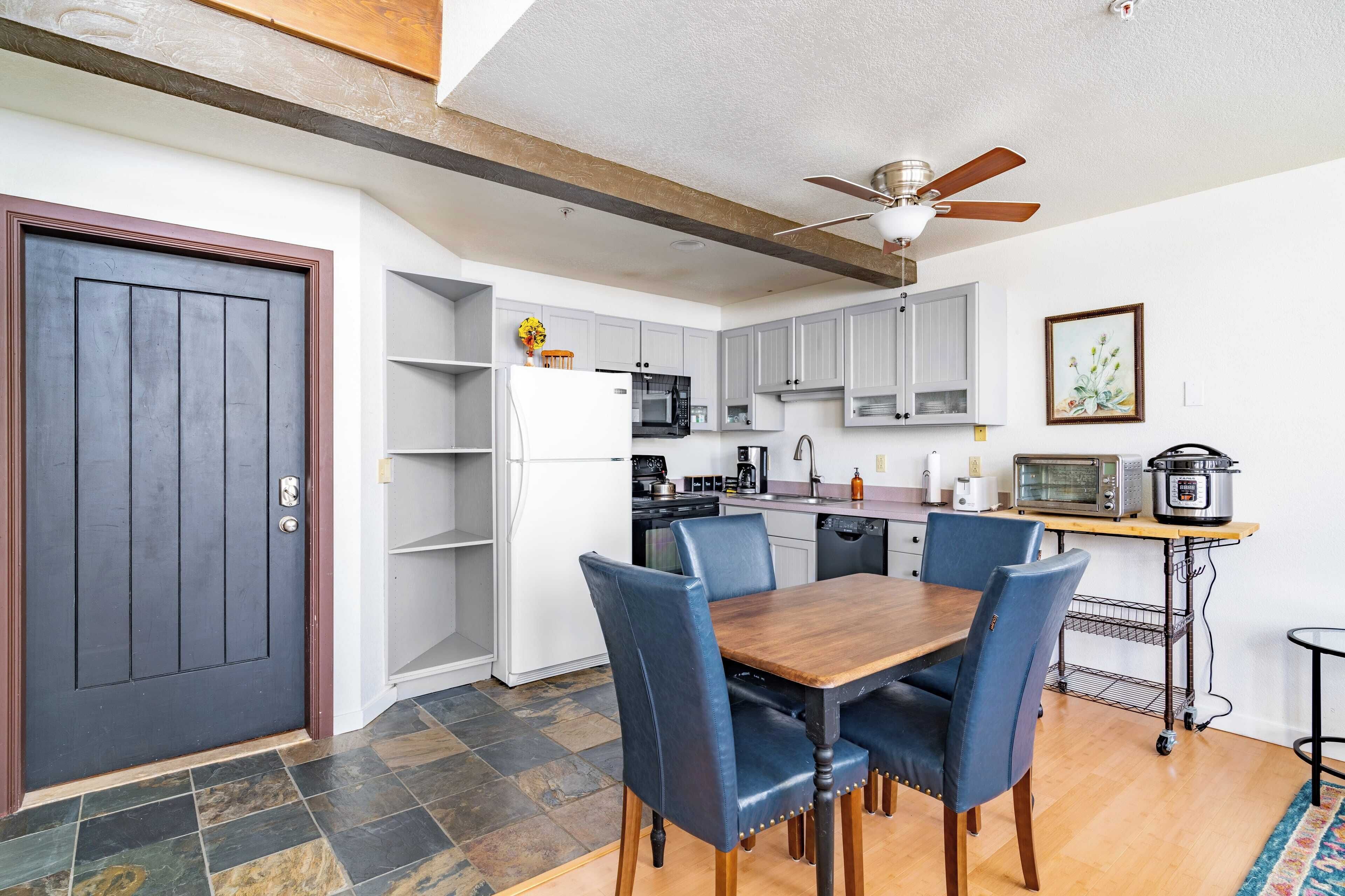 A compact kitchen with a dining table, chairs, and a ceiling fan.