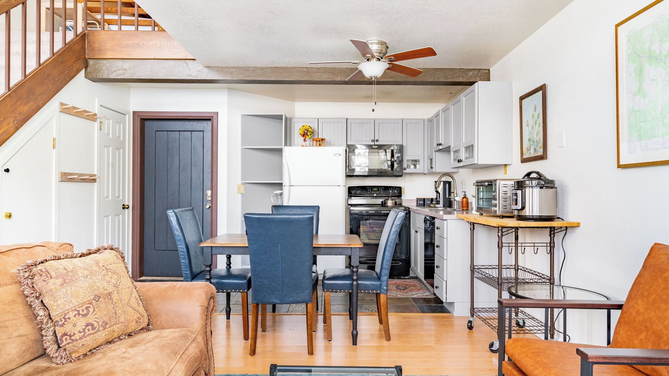 A compact living space with a dining area, kitchen, and a staircase.