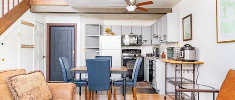A compact living space with a dining area, kitchen, and a staircase.