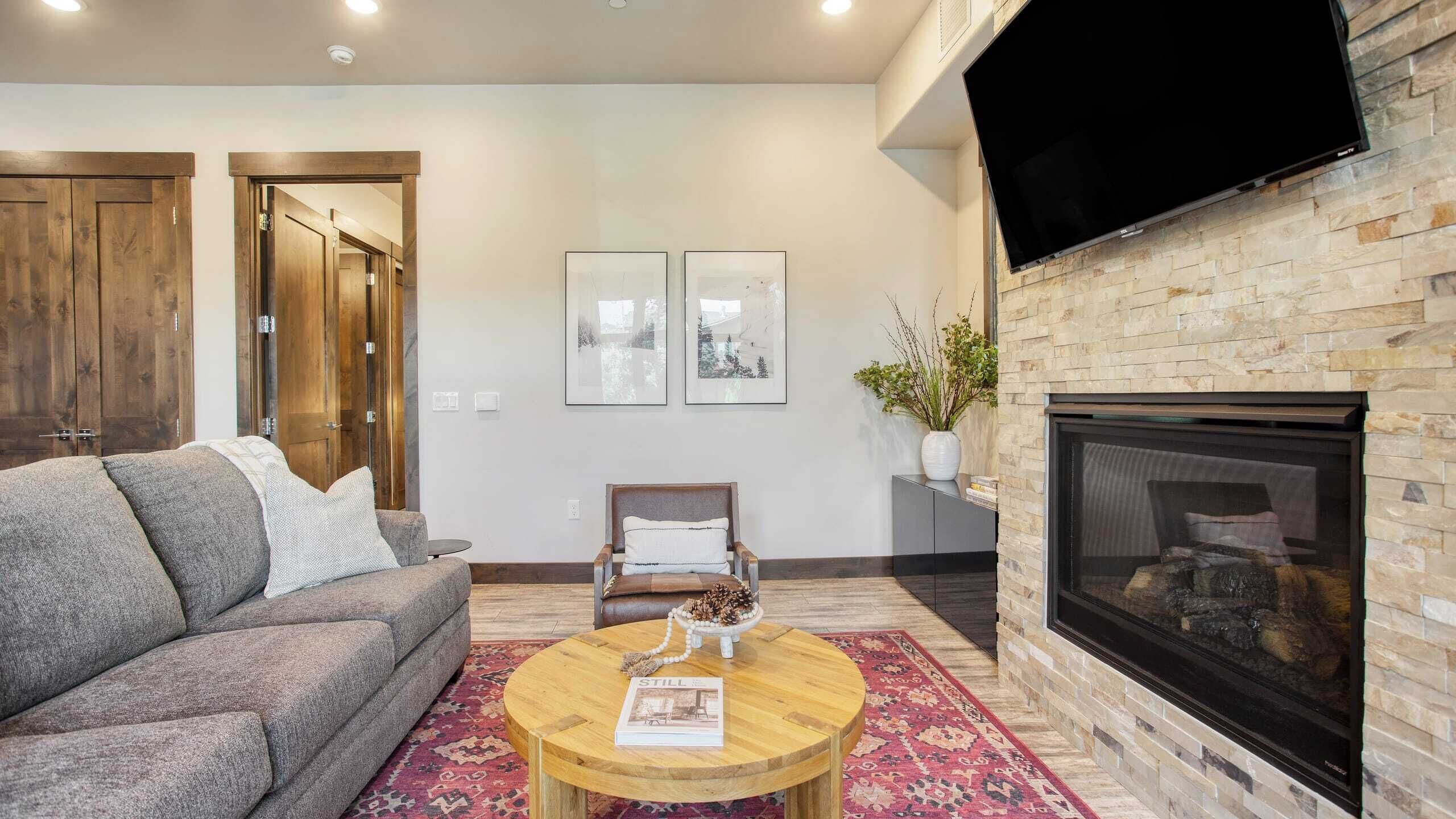 Un salon avec une cheminée, un canapé, une table basse et un téléviseur fixé au mur.