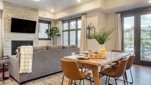 A modern living room with a fireplace, a sofa, and a dining area with a table and chairs. - Kestrel by Avantstay Close to the Ski Slopes in This Majestic Home in Park City (Park City)