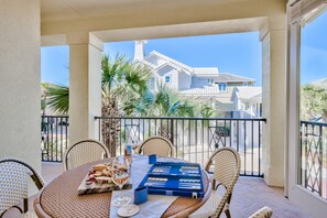 A balcony with wicker chairs, a table set with snacks, a bottle, and a glass.