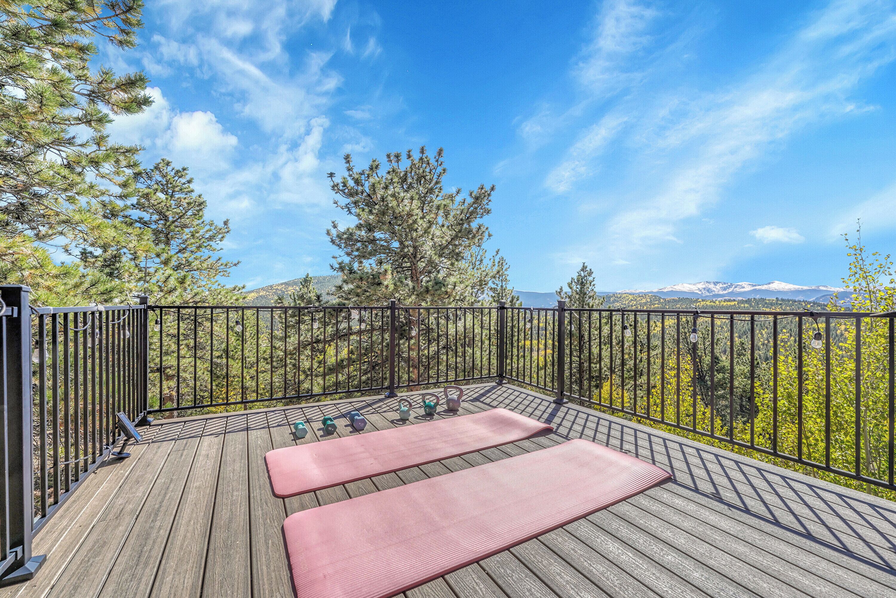 A wooden deck with exercise mats and weights, overlooking a mountainous landscape.