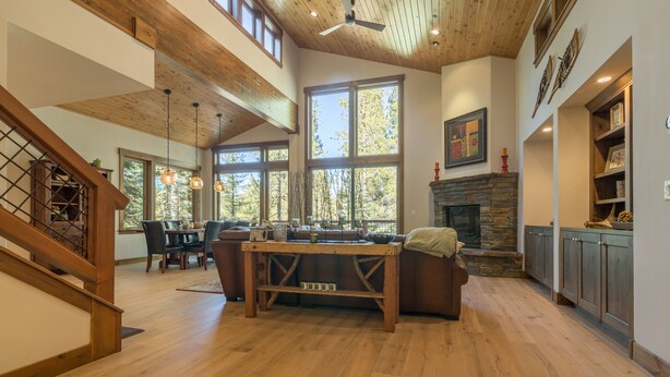 A spacious kitchen with a central island, wooden flooring, and large windows offering views of the outdoors. - Sawtooth by Avantstay Spacious Pine Tree Cabin w/ Hot Tub (Truckee)