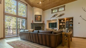 A spacious living room with a large sectional sofa, a fireplace, a television, and a wooden ceiling. - Sawtooth by Avantstay Spacious Pine Tree Cabin w/ Hot Tub (Truckee)