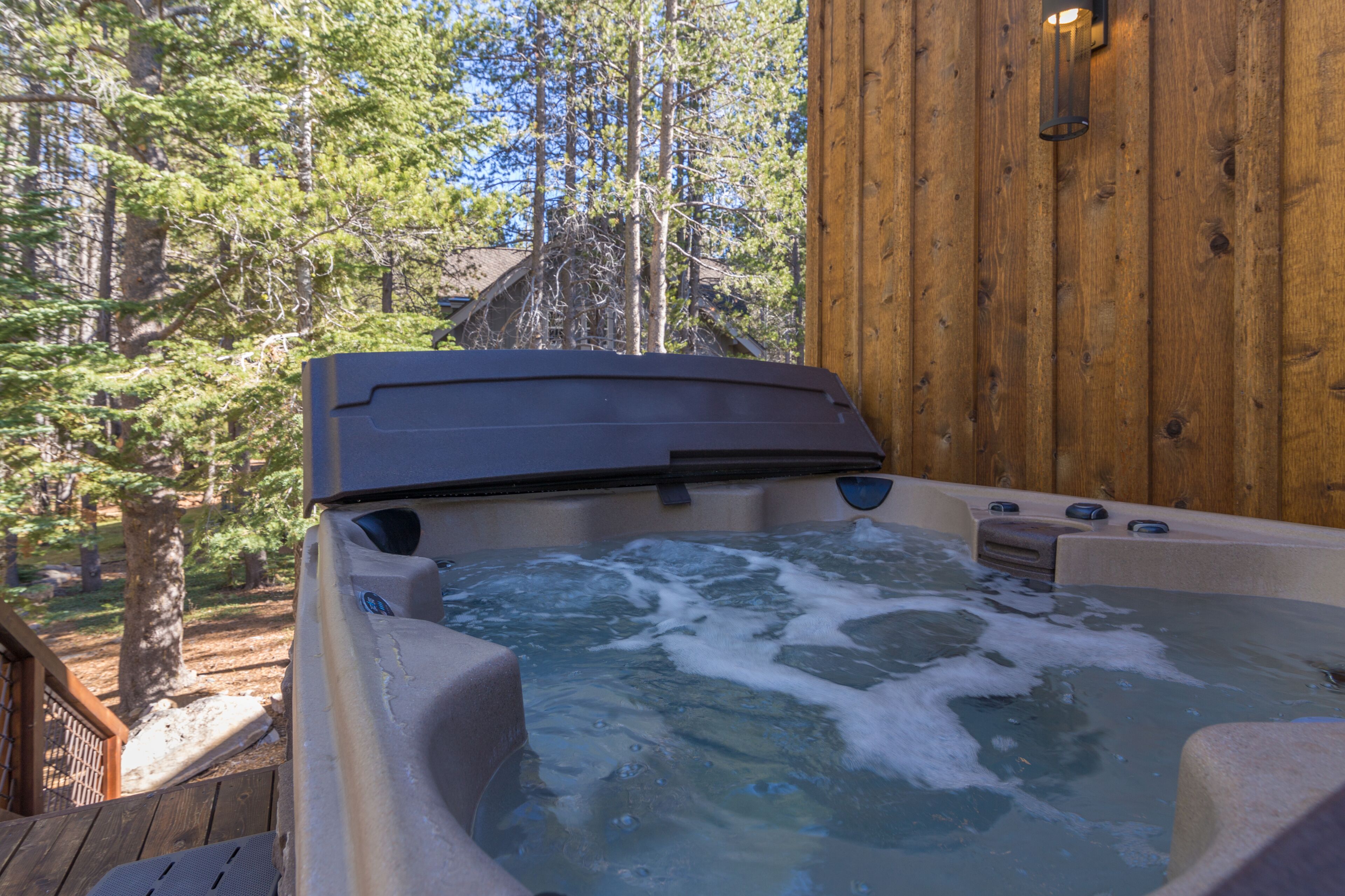 A hot tub with a wooden deck and a wooden wall in the background.