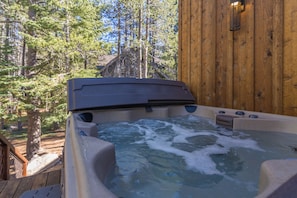 Ein Whirlpool mit einer Holzterrasse und einer Holzfassade im Hintergrund.