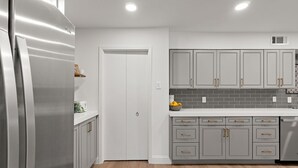 A modern kitchen with grey cabinets, a stainless steel refrigerator, and a white countertop. - 3 bdrm Sanctuary in the Heart of Dallas (Dallas)