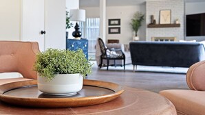 A living room with a round wooden table, a white bowl with green plants, a brown leather sofa, and a black sofa. - 3 bdrm Sanctuary in the Heart of Dallas (Dallas)