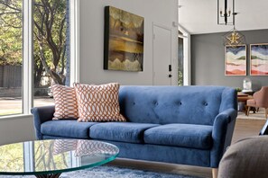 Relax in this inviting living room with a sofa, coffee table, and a beautiful view of the surrounding trees.