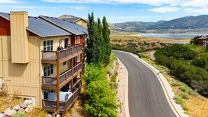 A multi-story building with balconies, a curved road, and a mountainous landscape in the background.