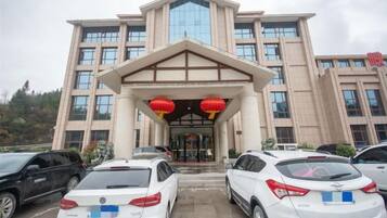 A multi-story building with a prominent entrance, several parked cars, and red lanterns above the entrance.
