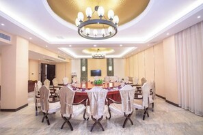 Un salón de conferencias con una mesa redonda, sillas y una araña.