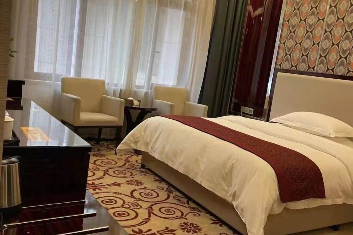 Una habitació d'hotel amb un llit, dues cadires, un escriptori i una cafetera.