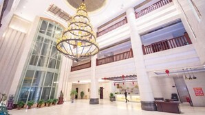 A spacious lobby with a large chandelier, multiple floors, and a reception desk. - Yesanguan International Hotel (Badong)