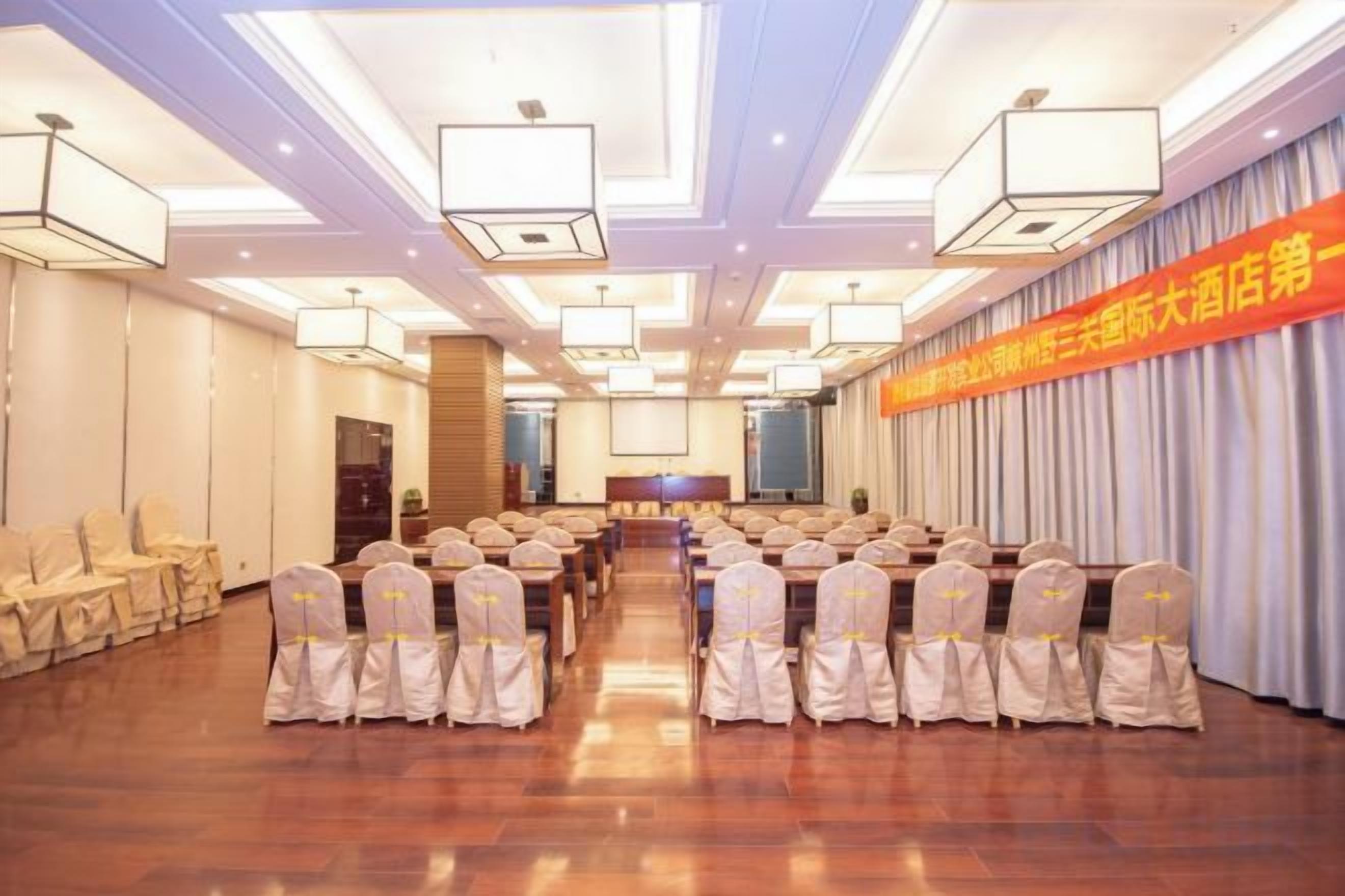A conference room with rows of chairs, a stage, and a banner on the wall.