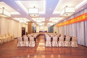 A conference room with rows of chairs, a stage, and a banner on the wall. - Yesanguan International Hotel (Badong)