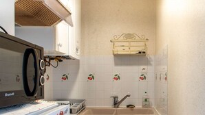 A compact kitchen with a Brandt refrigerator, a sink, and a small window above the sink. - Sea-view apartment with two balconies in Erquy | 4 guests | Ref 442 (ERQUY)