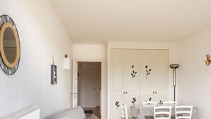 A room with a white door, a mirror, a small table with chairs, and a radiator. - Sea-view apartment with two balconies in Erquy | 4 guests | Ref 442 (ERQUY)
