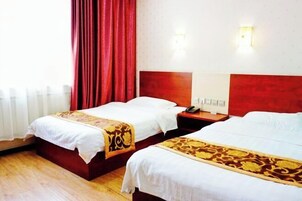 Habitación de hotel con dos camas, cabecera de madera, cortina roja y mesita de noche con teléfono.