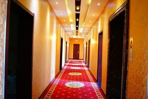 A hotel hallway with a red carpet, doors on both sides, and a patterned wall. - Jinyulan Hotel (Manzhouli)