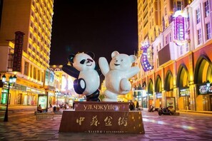 A nighttime street scene with two large panda statues, a sign with Chinese characters, and illuminated buildings.