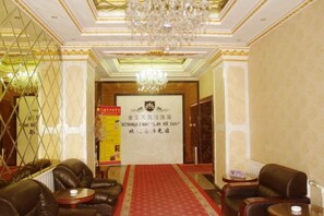 A hotel lobby with leather sofas, a red carpet, a chandelier, and a banner with text. - Jinyulan Hotel (Manzhouli)