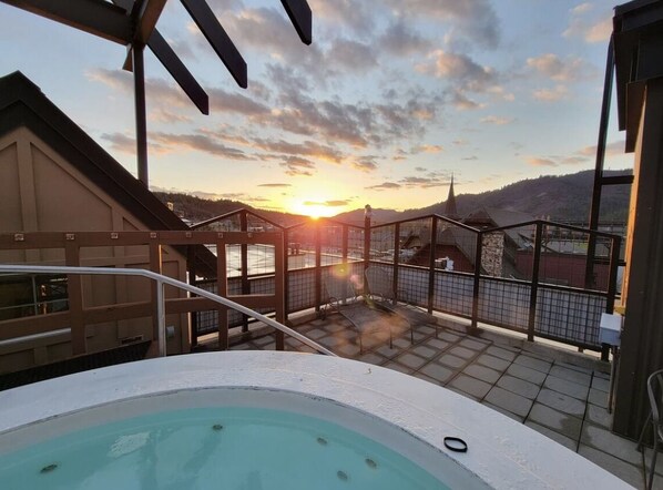 Una piscina en la azotea con vistas a la puesta de sol sobre un paisaje montañoso.
