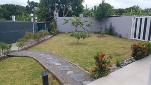 A landscaped garden with a stone pathway, small trees, and flowering plants. - HONEY HOUSE VILLA WITH PRIVATE RIVER (Petit-Bourg)