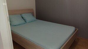 A single bed with a light blue mattress and matching pillows, a wooden headboard, and a plain grey wall. - HONEY HOUSE VILLA WITH PRIVATE RIVER (Petit-Bourg)