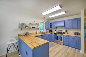 Una cocina moderna con armarios azules, encimera de madera y electrodomésticos de acero inoxidable.