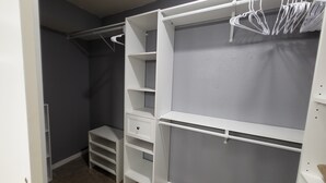 Ein begehbarer Kleiderschrank mit offene Regale, einer Kleiderstange und einer kleinen Stauraum-Einheit.