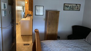 A bedroom with a bed, a wooden wardrobe, a small bathroom with a sink, and a ceiling fan. - Cheerful 2 Bed & 1Bath unfinished home with beautiful views (Cordes Lakes)