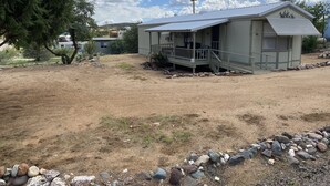 A small, single-story house with a porch and a satellite dish. - Cheerful 2 Bed & 1Bath unfinished home with beautiful views (Cordes Lakes)