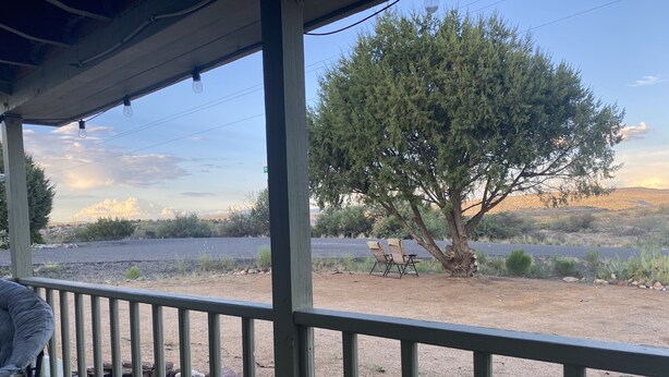 A wooden deck with a railing, overlooking a natural landscape with a large tree and a body of water. - Cheerful 2 Bed & 1Bath unfinished home with beautiful views (Cordes Lakes)