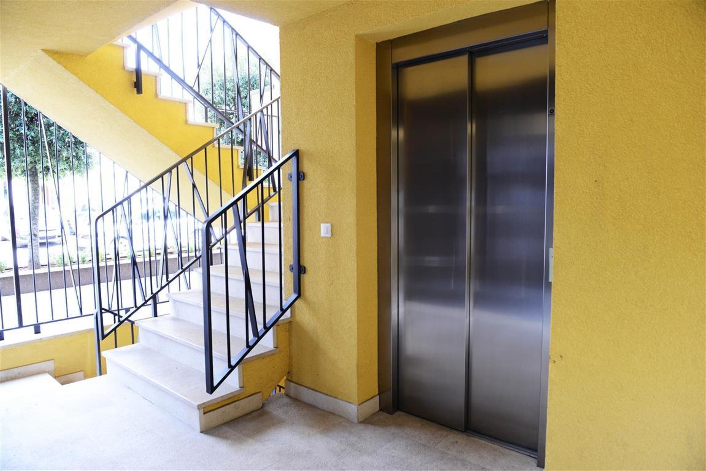 A yellow building with a staircase and an elevator.