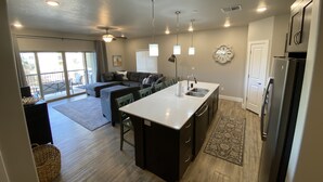 A modern kitchen with a central island, built-in appliances, and a dining area with a large window.