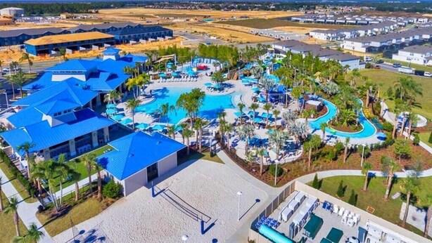 Un complexe hôtelier doté de plusieurs piscines, de palmiers et d’un grand bâtiment surmonté d’un toit bleu.