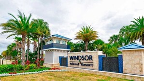Un panneau indiquant le « Windsor Island Resort », avec des palmiers et un bâtiment en arrière-plan.