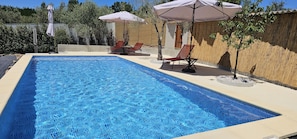 Una piscina al aire libre de temporada, sombrillas