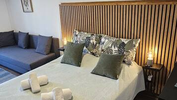 A modern bedroom with a large bed, a wooden headboard, and a blue sofa.
