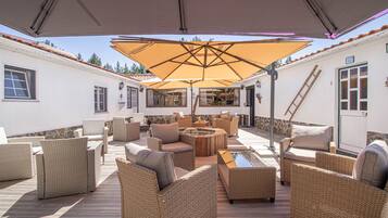 A covered outdoor seating area with wicker furniture and a central fire pit.