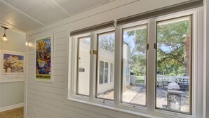 A hallway with white paneled walls and large windows.