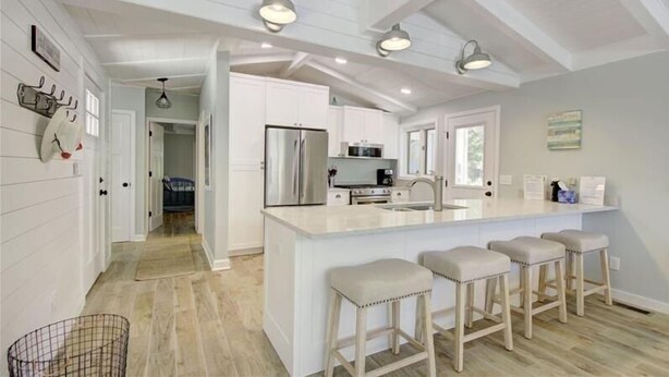 A modern kitchen with white cabinetry, a large island with bar stools, and pendant lighting.