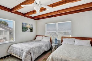 A bedroom with two beds, wooden beams on the ceiling, a ceiling fan, and a painting on the wall. - Bill Smith House B - great location with ocean views (Jekyll Island)