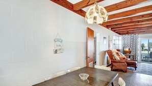 A modern living room with a wooden ceiling, a dining table with chairs, a sofa, and a television. - Bill Smith House B - great location with ocean views (Jekyll Island)