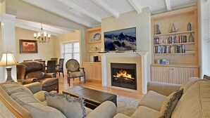 Ein Wohnzimmer mit Kamin, gemütlicher Sitzgelegenheit, Fernseher und Bücherregal.