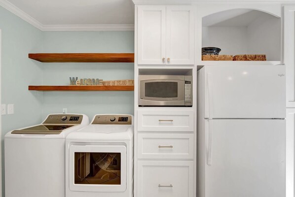 A compact kitchen with a washing machine, a microwave, and a refrigerator. - Newbern Cottage - fabulous cottage only 2 blocks from the beach (Jekyll Island)