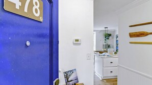 A room with a blue door labeled '478', a thermostat, a kitchen area with white cabinets, and wooden paddles on the wall. - Villas by the Sea 478 (Jekyll Island)