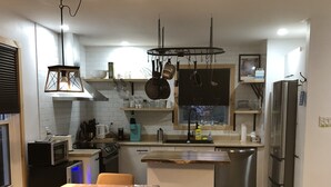 A modern kitchen with a central island, stainless steel appliances, and a dining area with a table and chairs. - MAgog~Condo C.O.Z.Y. Cocooning ~ Lake Memphré (Magog)